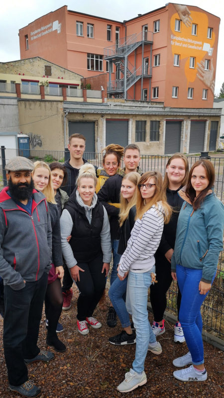 Eine Gruppe von Schülern und Schülerinnensteht vor der Schule und posiert,