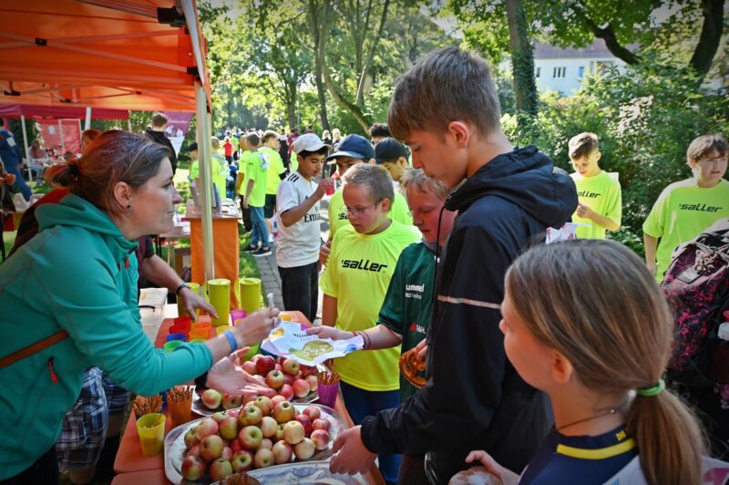 Einne Gruppe Personen steht an eonem Stand mit Essen.