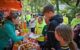 Einne Gruppe Personen steht an eonem Stand mit Essen.