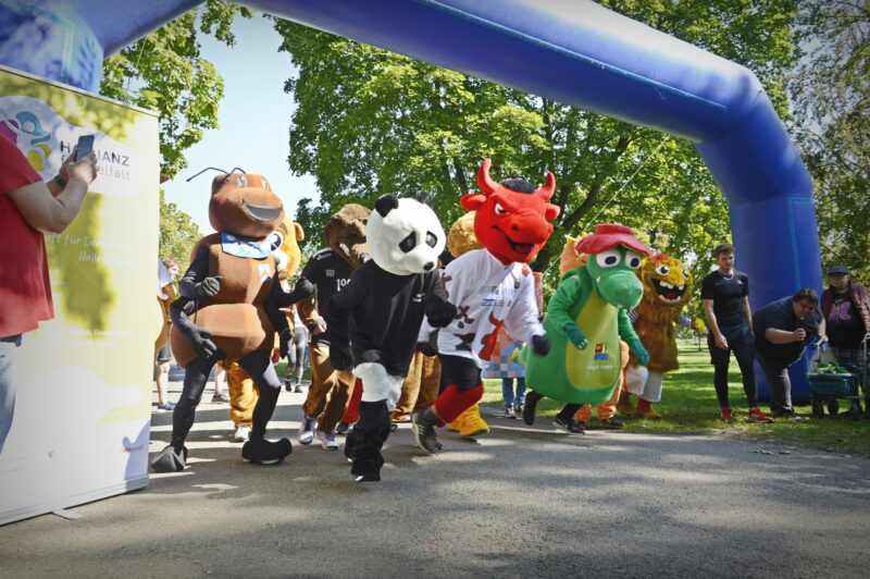 Eine Gruppe Maskottchen läfut an einer Startlinie los.