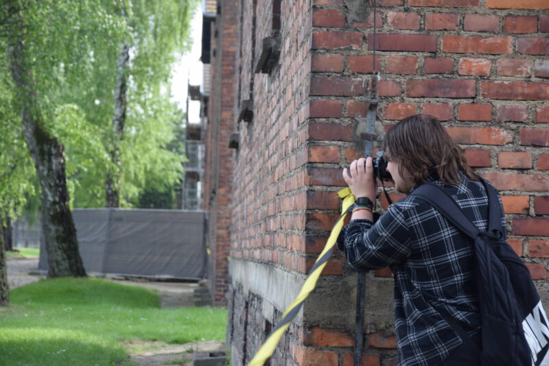 Eine Person steht draußen und fotografiert etwas.